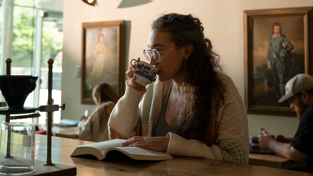 Woman sipping coffee while reading a book